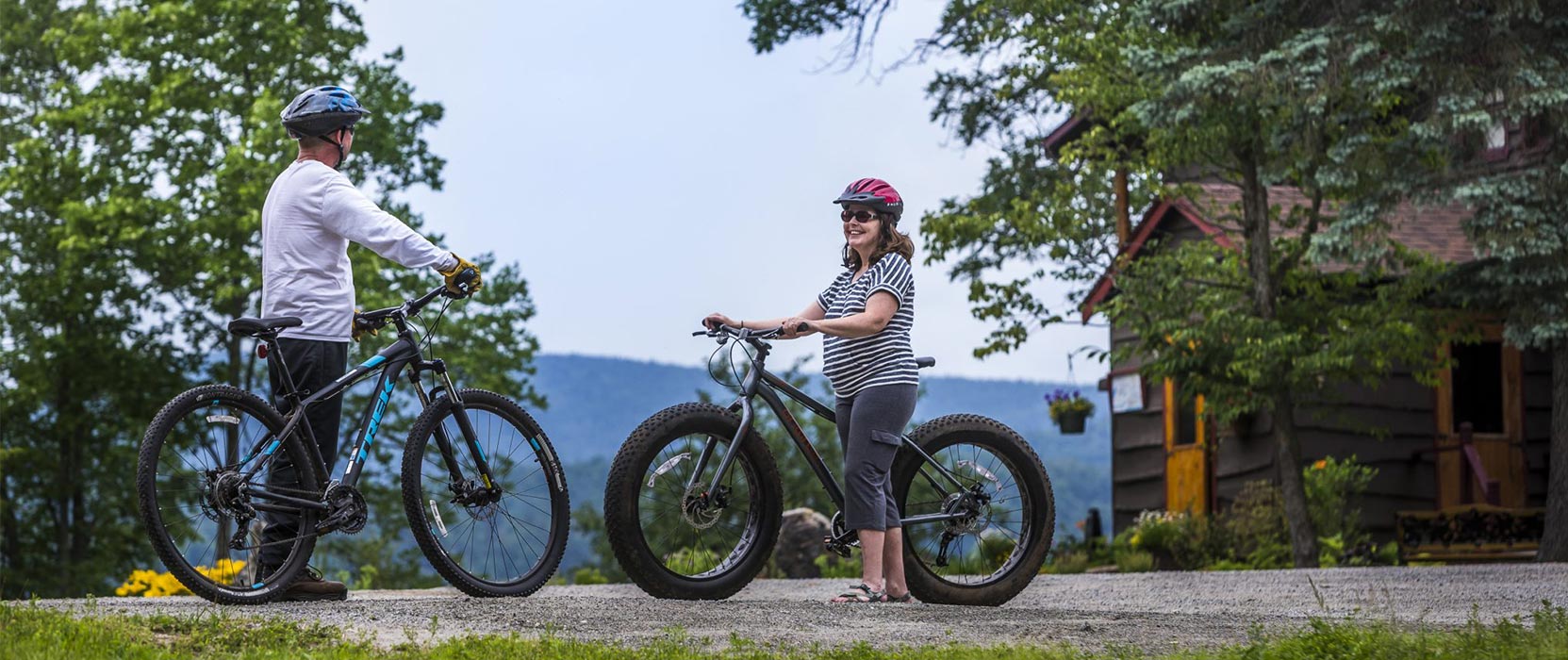 Two people holding mountain bikes with Garnet Hill Lodge in the background
