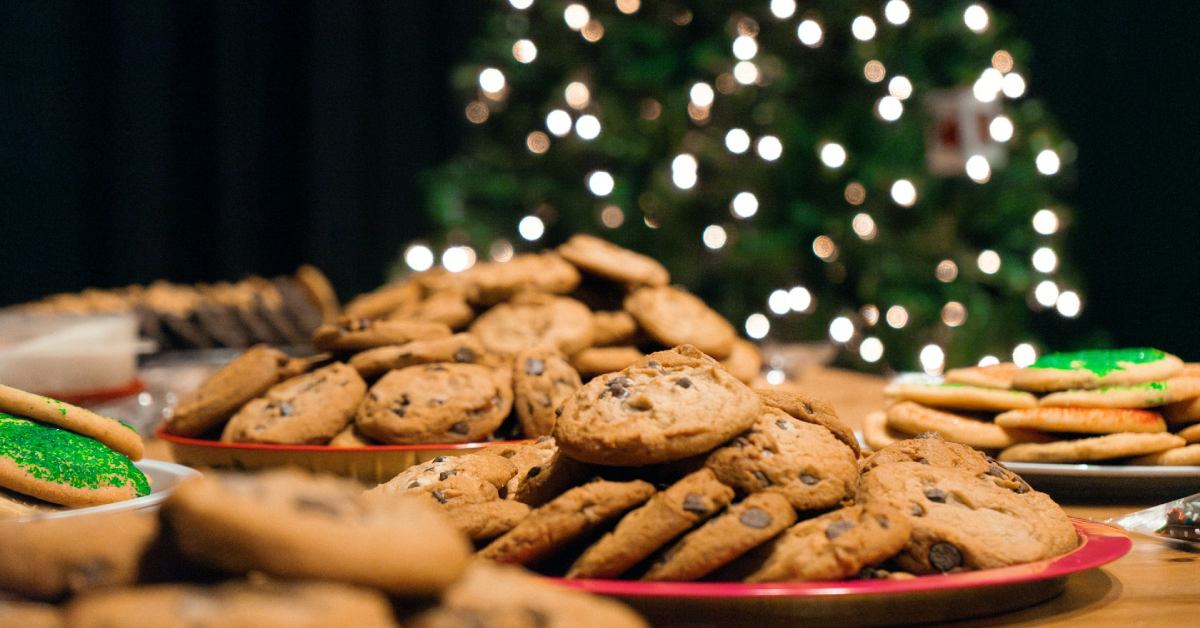 plates of cookies in front of a lit up christmas tree