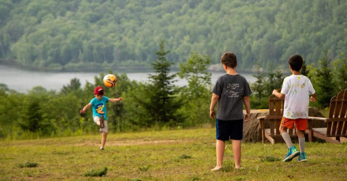 group of three kids playing with a soccer ball on a warm afternoon