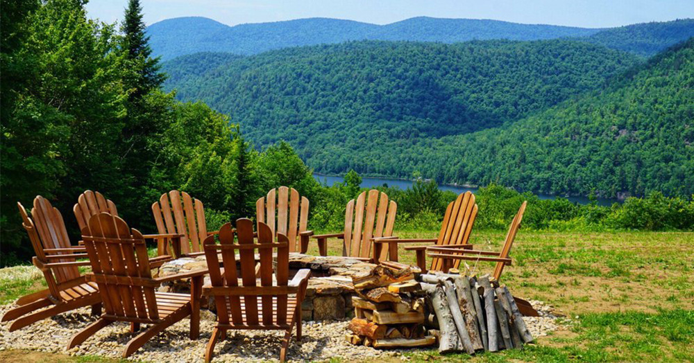 fire pit with adirondack chairs and a lake and mountain view in the background