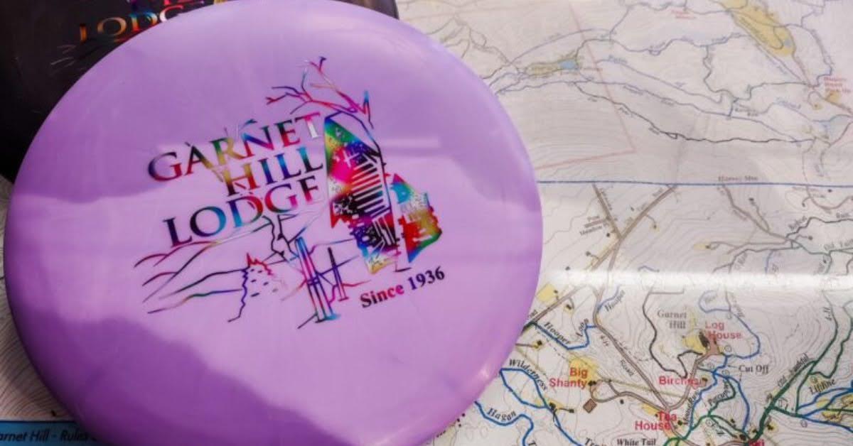 purple disc golf disc with garnet hill lodge logo on it