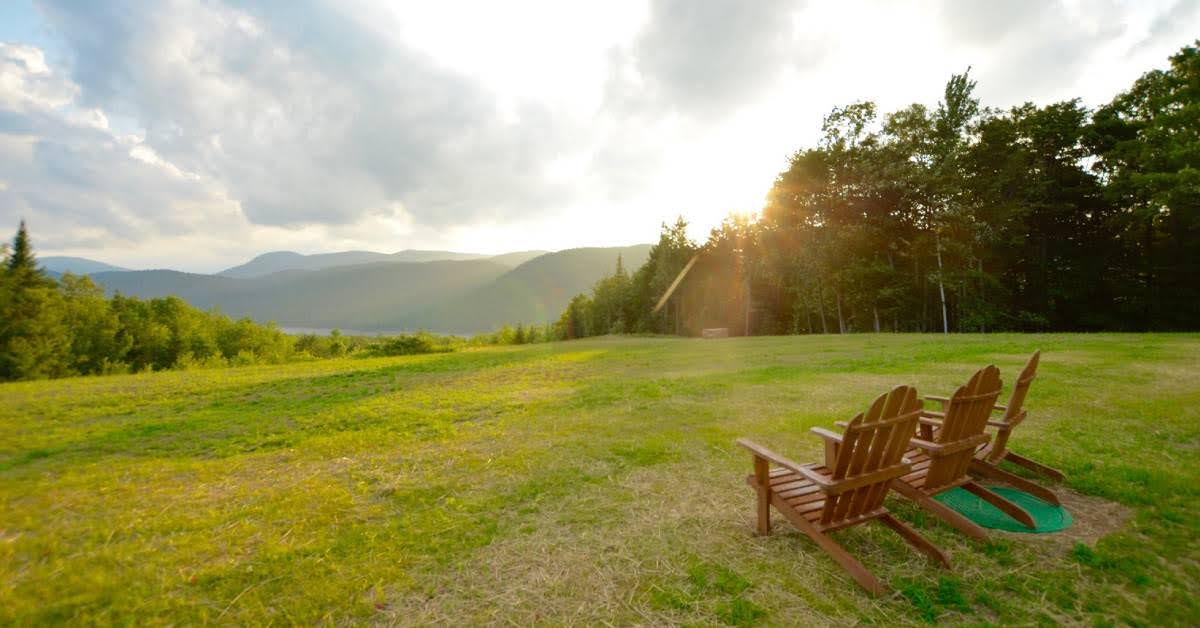 three adirondack chairs looking over thirteeth lake with mountains in the background