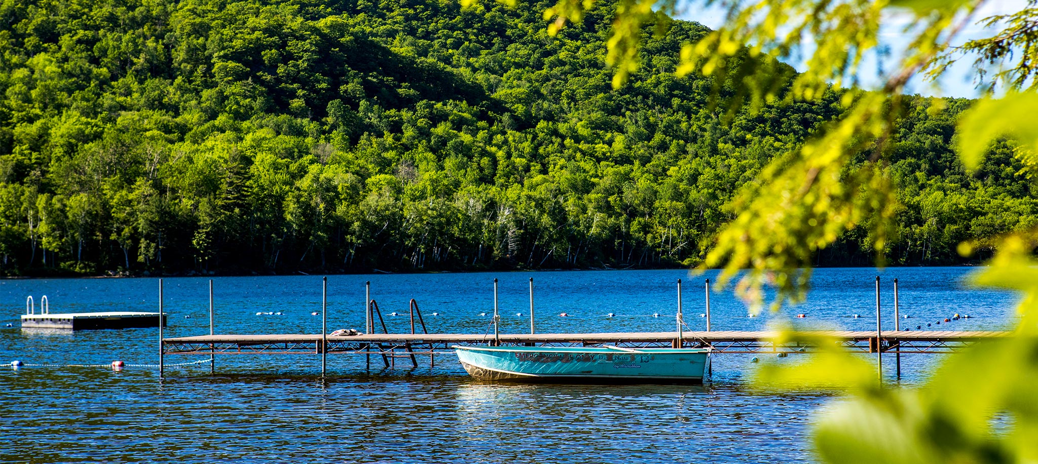 teal rowboat docked on thirteenth lake