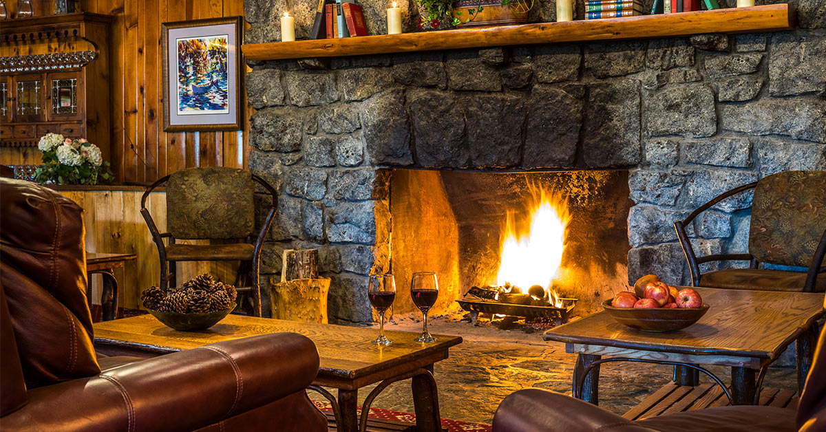 stone fireplace with two glasses of red wine in front of it