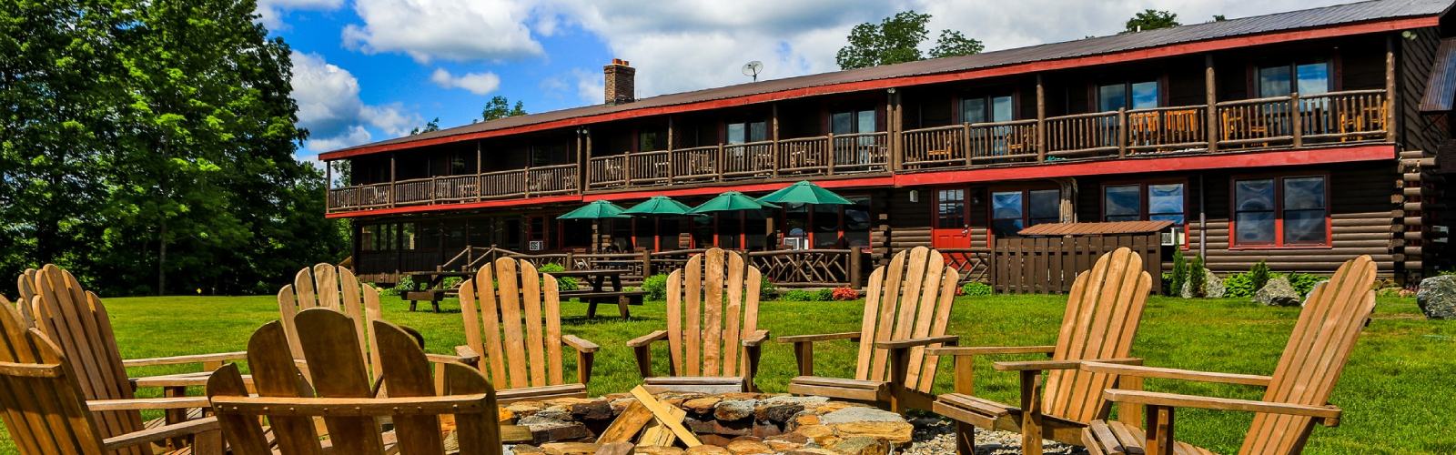 exterior of garnet hill lodge with adirondack chairs around a fire pit