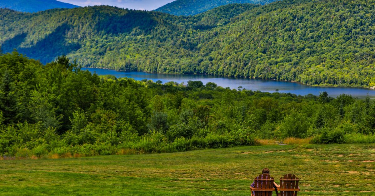 adirondack chairs looking out at view of a river and mountains